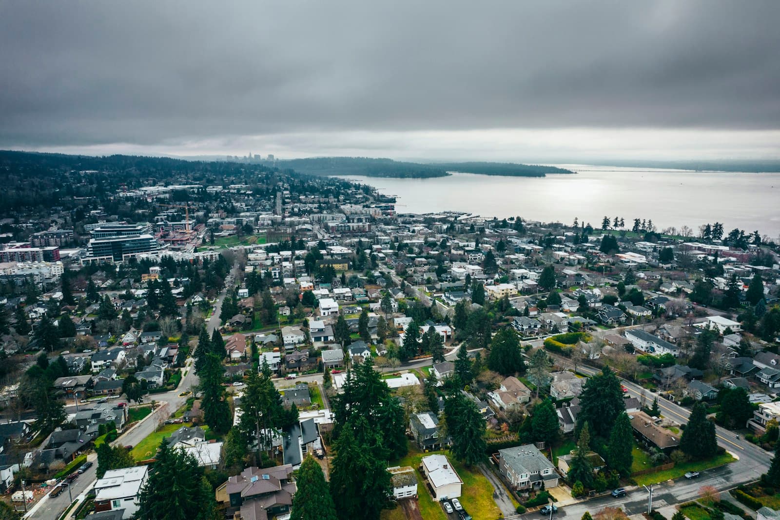 Aerial view of suburban coastal town with residential neighborhoods overlooking water under cloudy sky